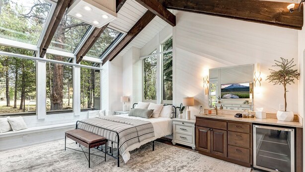Une chambre à coucher avec un grand lit, un banc, une commode, un miroir et un four encastré.