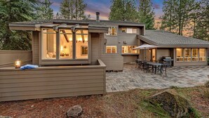 Une maison moderne dotée d’un patio, de grandes fenêtres et d’une cheminée.