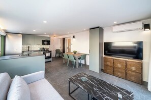 Un espace de vie moderne comprenant une cuisine, un coin repas et un téléviseur.