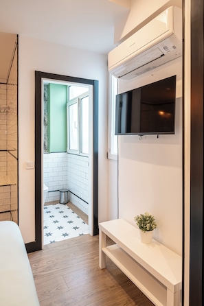 Un baño moderno con ducha, inodoro y un pequeño banco con planta en maceta.