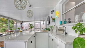 A modern kitchen with white cabinets, a large island, and a view of the backyard. - Catalina Hideaway - Heated Pool - Game Room (Indian Harbour Beach)
