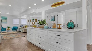 A modern kitchen with white cabinetry, a central island, and a herringbone wood floor. - Catalina Hideaway - Heated Pool - Game Room (Indian Harbour Beach)