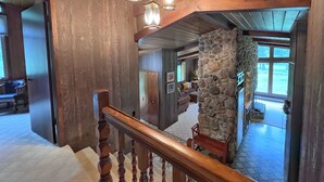 A wooden staircase with a stone wall and a view of a living room with a stone fireplace. - Secluded Setting On French Creek In The Southern Black Hills (Custer)