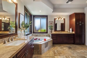 Un baño moderno con una bañera grande, lavamanos dobles y muebles de madera oscura.