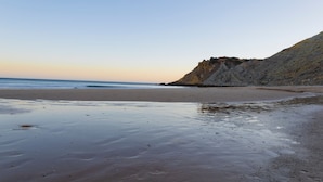 Una playa con un acantilado rocoso y agua tranquila.