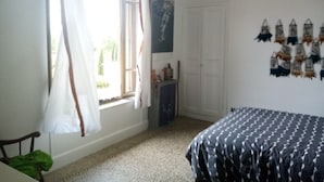 Un dormitorio con cama, ventana con cortinas, armario y decoración en la pared.