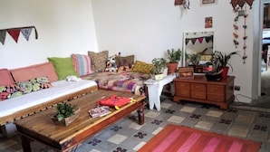 Una sala de estar acogedora con un sofá, una mesa de centro de madera, un tapete estampado y un aparador con adornos.