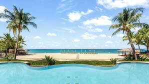 A swimming pool with a view of a beach and palm trees. - Beachcomber 3 by Grand Cayman Villas (7 Mile Beach)