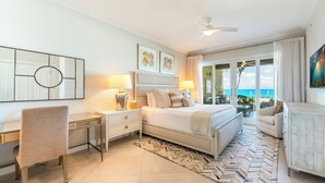A bedroom with a bed, desk, chair, and a view of the ocean. - Beachcomber 3 by Grand Cayman Villas (7 Mile Beach)