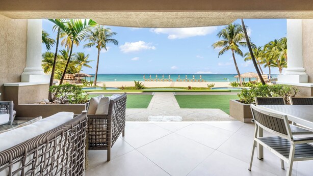 A covered outdoor seating area with a view of the beach and ocean. - Beachcomber 3 by Grand Cayman Villas (7 Mile Beach)