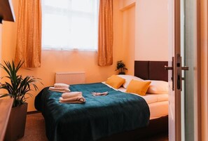 Un lit bien fait, recouvert d’une courtepointe turquoise, avec deux oreillers et des serviettes pliées posées sur le côté.
