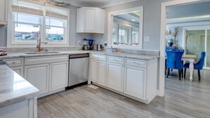 A modern kitchen with white cabinetry, a dishwasher, and a large window.