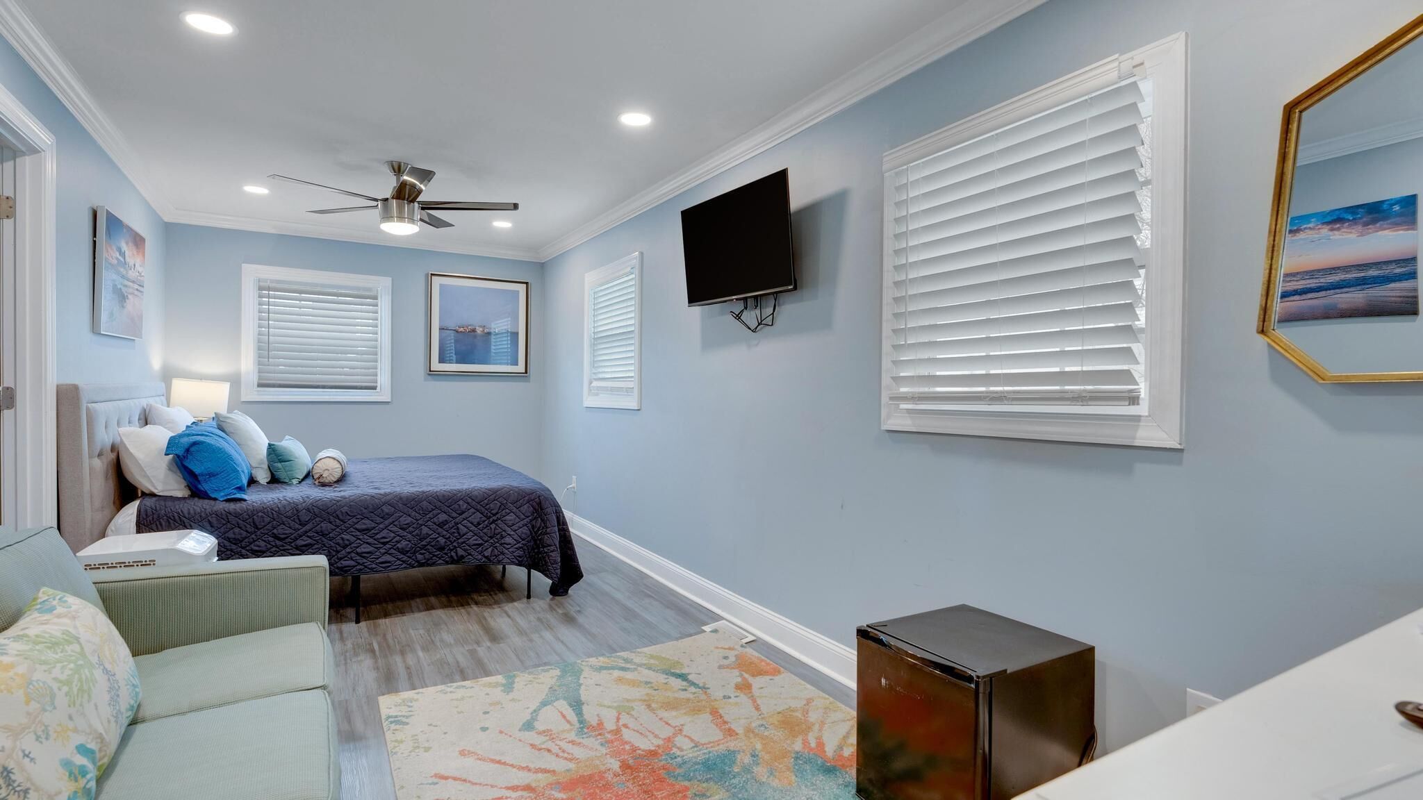 A bedroom with a bed, a TV, and a ceiling fan.