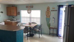 A kitchen with a dining area, wooden cabinets, a chandelier, and a refrigerator.