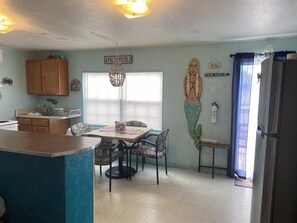 A kitchen with a dining area, wooden cabinets, a chandelier, and a refrigerator.