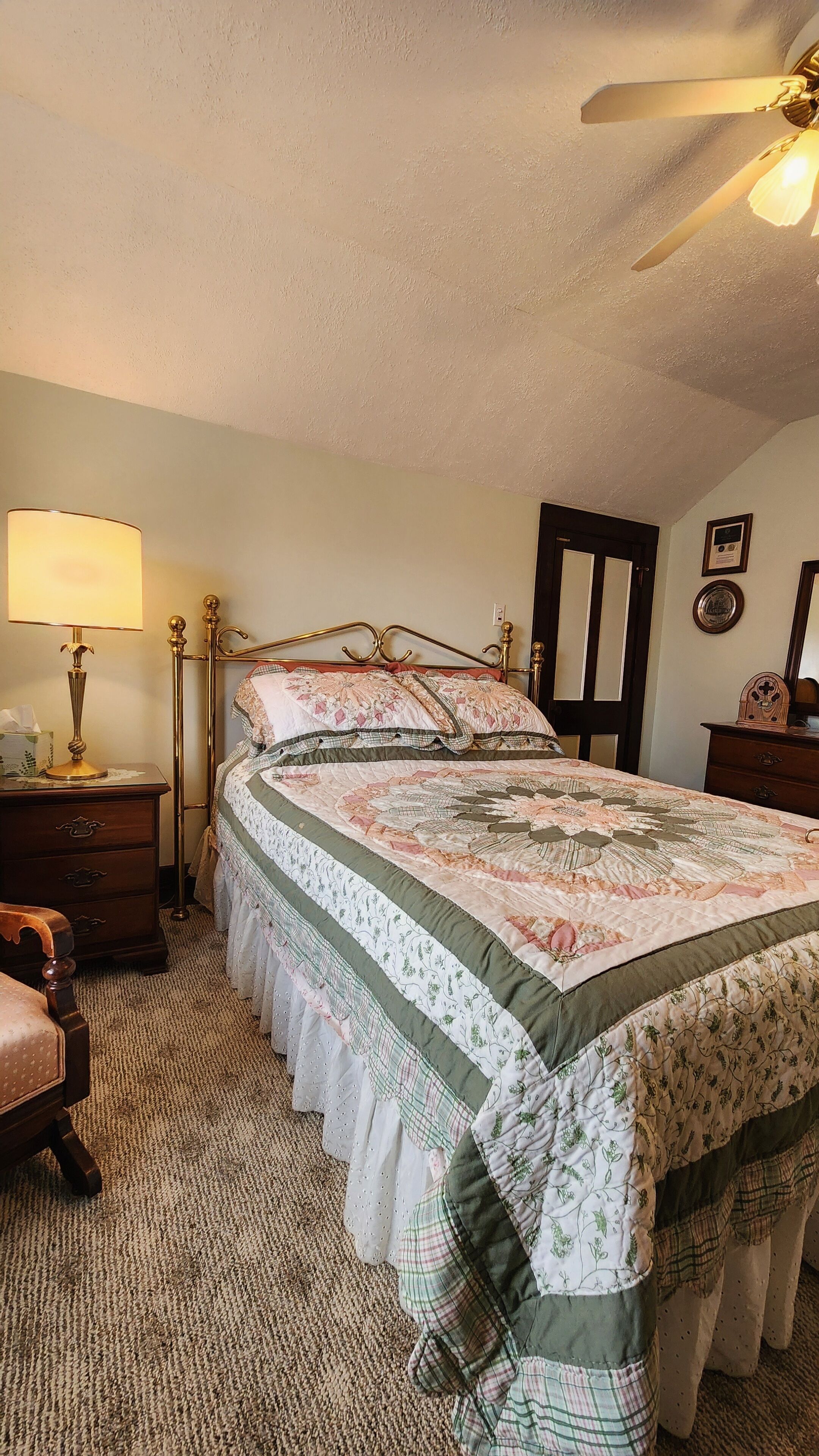 A bedroom with a bed, a nightstand, a lamp, a dresser, and a ceiling fan.