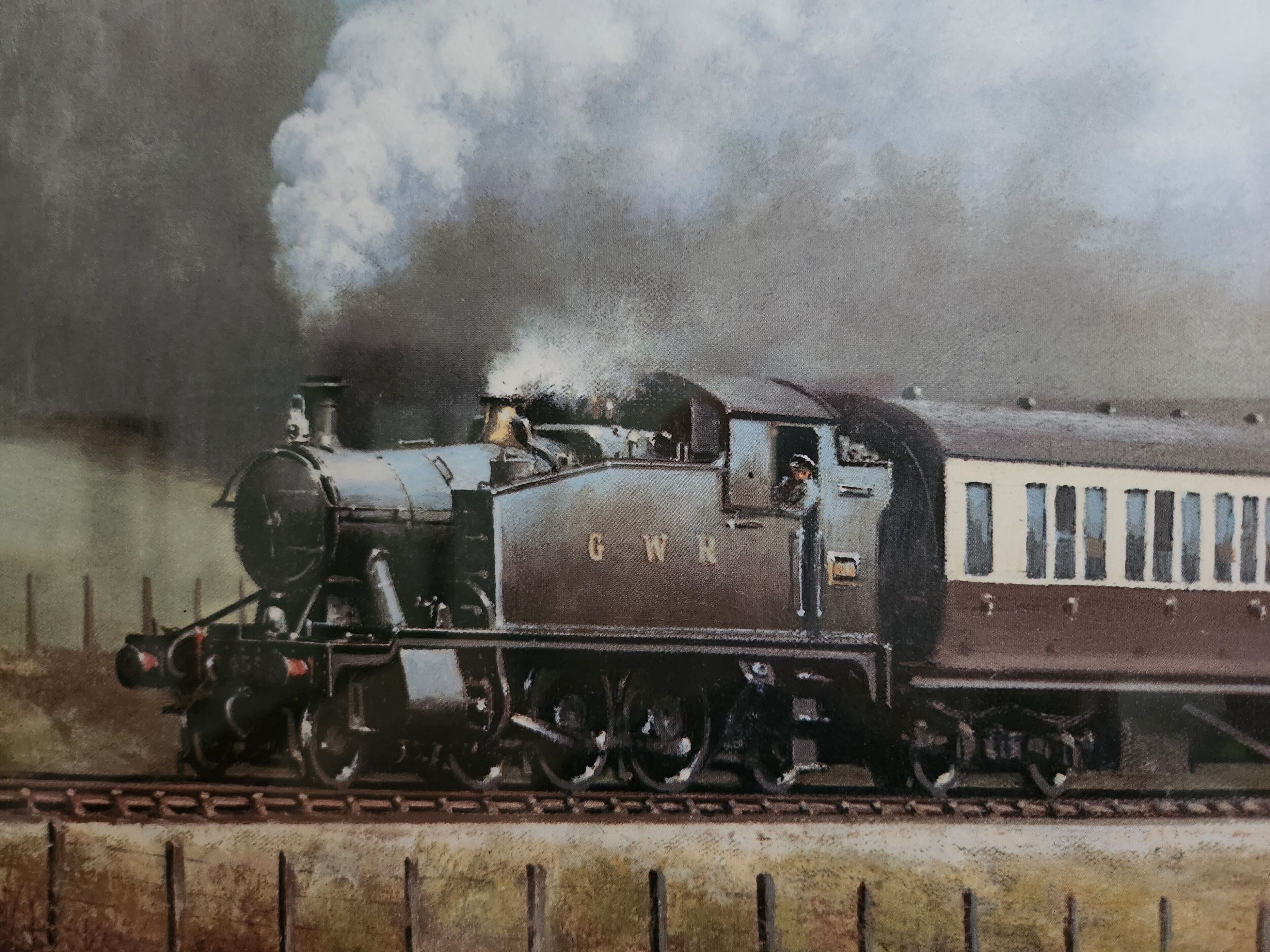 A vintage steam locomotive with the letters "GWR" on its side, traveling on a railway track.