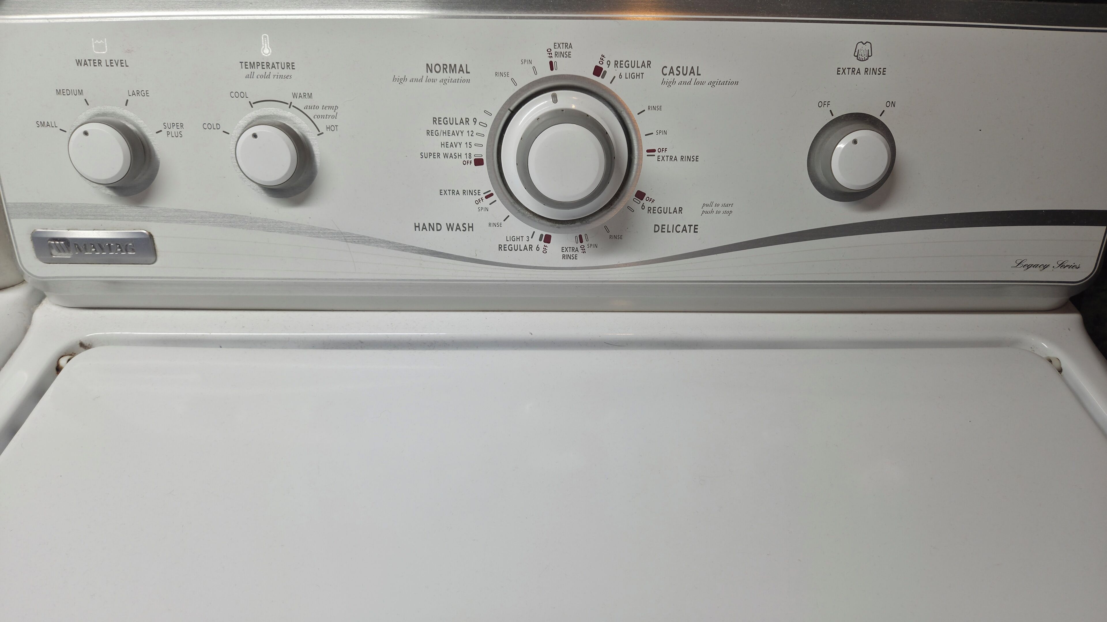 Een witte wasmachine met drie bedieningsknoppen voor waterstand, temperatuur en centrifuge-instellingen.