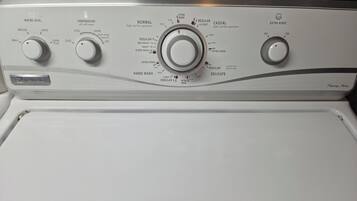 Een witte wasmachine met drie bedieningsknoppen voor waterstand, temperatuur en centrifuge-instellingen.