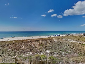 A beach with a sandy shore, a wooden fence, and a clear blue sky.