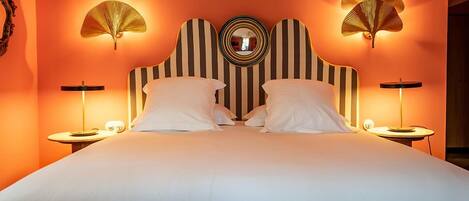 Una habitación de hotel con una cama grande, dos mesitas de noche y lámparas de pared.