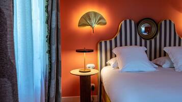 A hotel room with a bed, a bedside lamp, a wall-mounted fan, and a mirror.