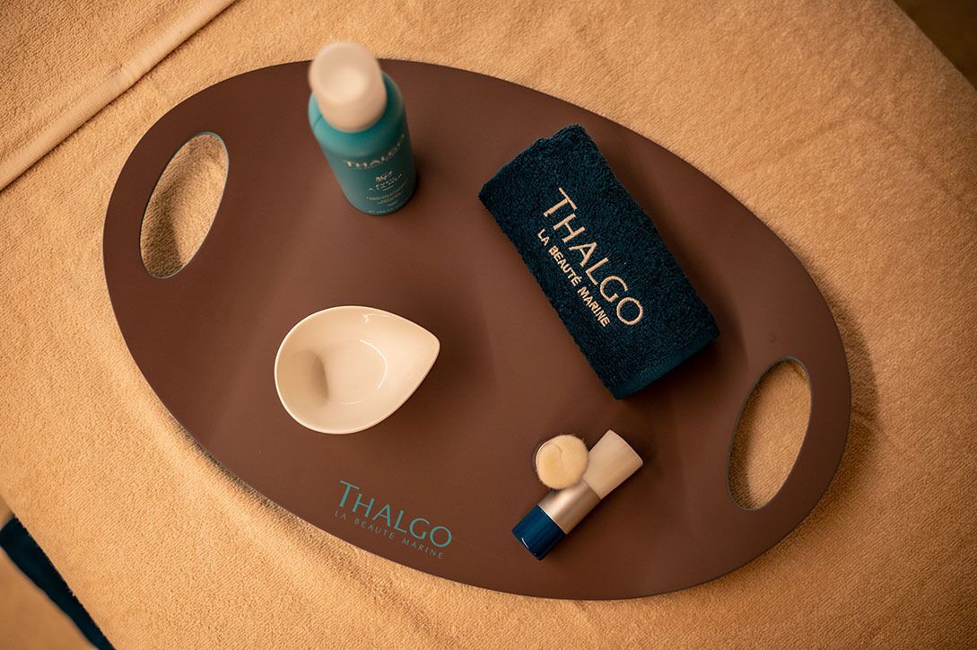 Een dienblad met Thalgo verzorgingsproducten, een handdoek en een gezichtsmasker.