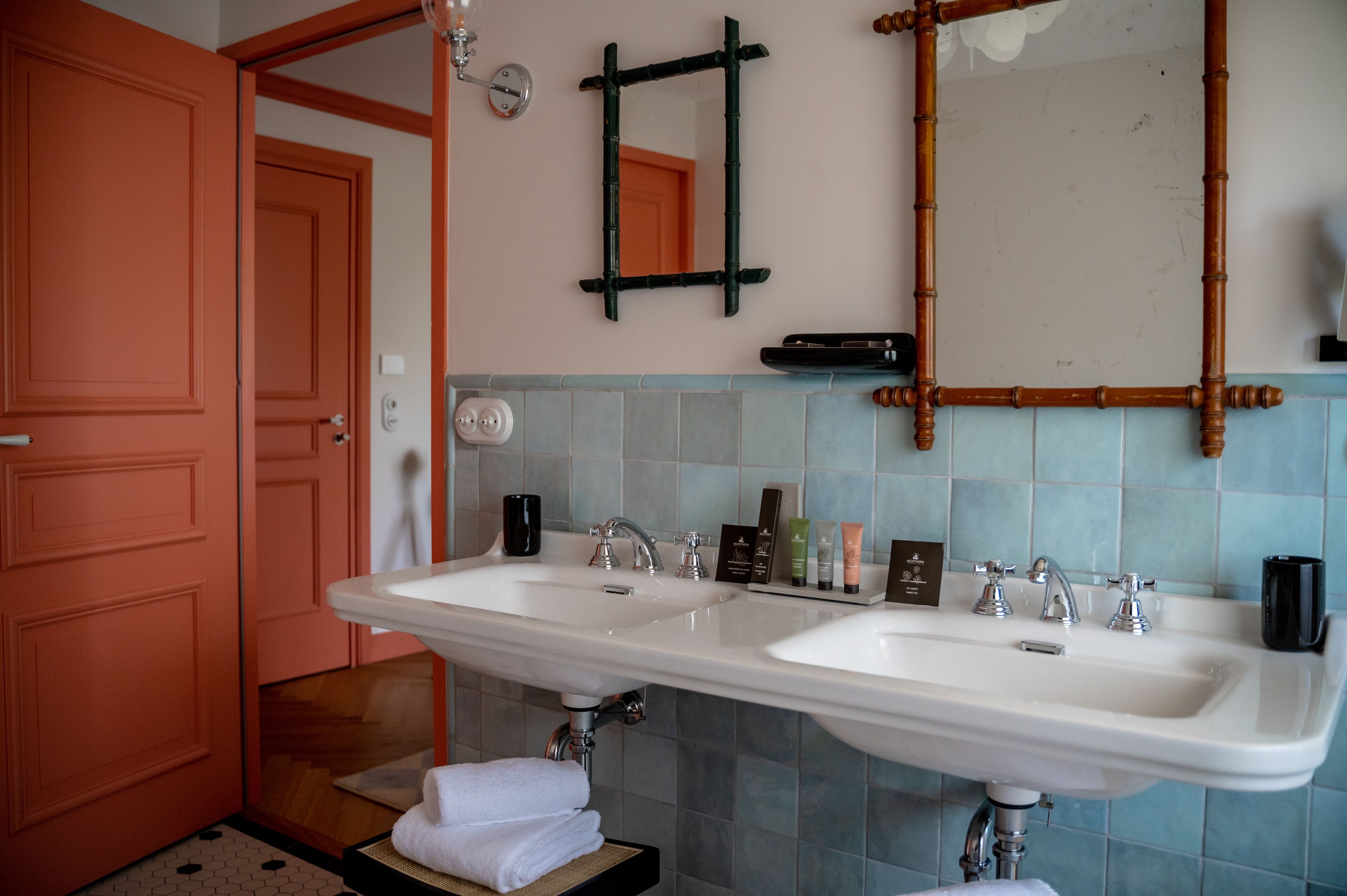 A bathroom with two sinks, a mirror, and toiletries on the countertop.