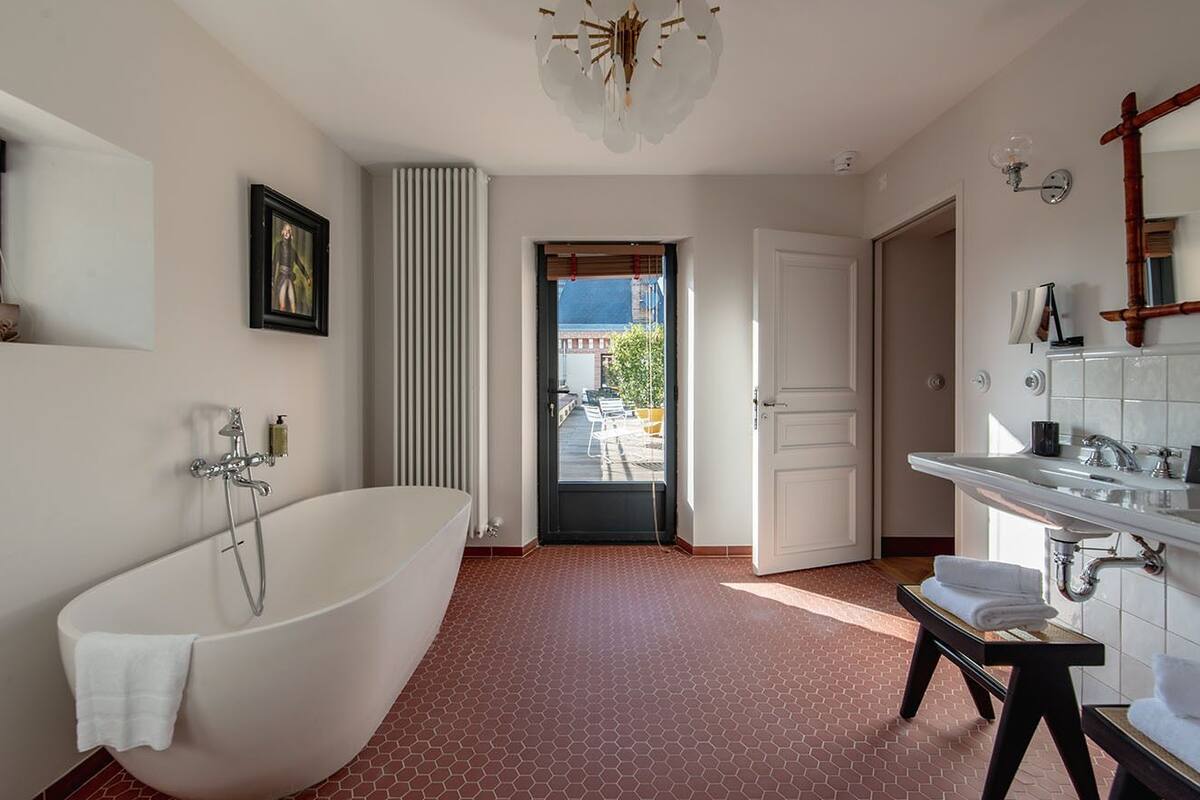 Une salle de bain moderne avec une baignoire sur pieds, un grand miroir et une vue sur l’extérieur.