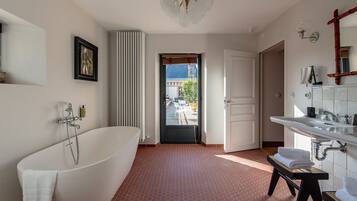 Ein modernes Badezimmer mit einer freistehenden Badewanne, einem großen Spiegel und Blick ins Freie.
