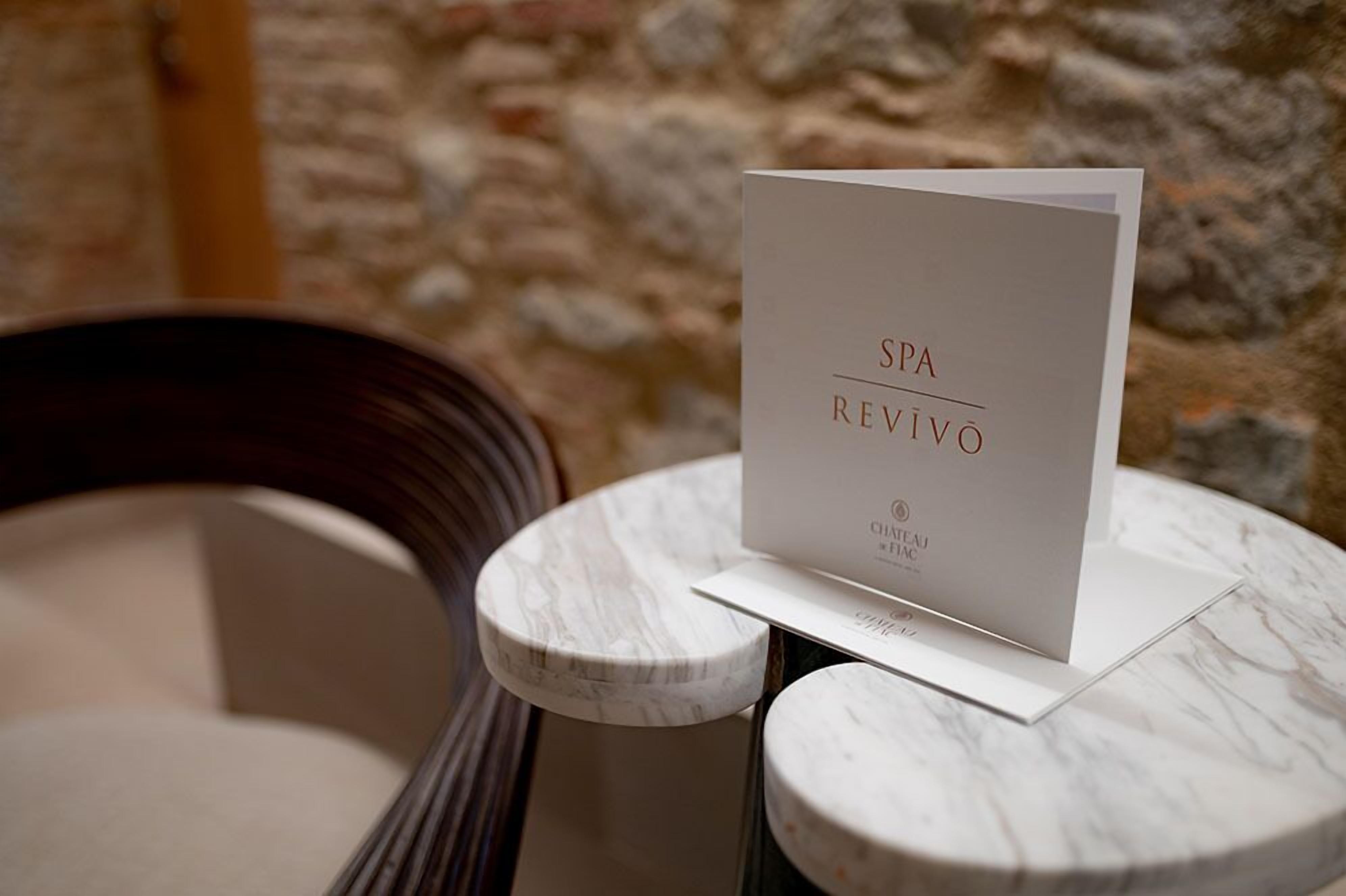 A SPA REVIVO sign on a marble table with a stone wall background.