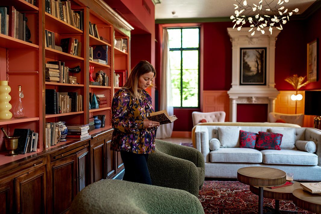 A cozy living room with a fireplace, a bookshelf filled with books, and a comfortable sofa with decorative pillows.