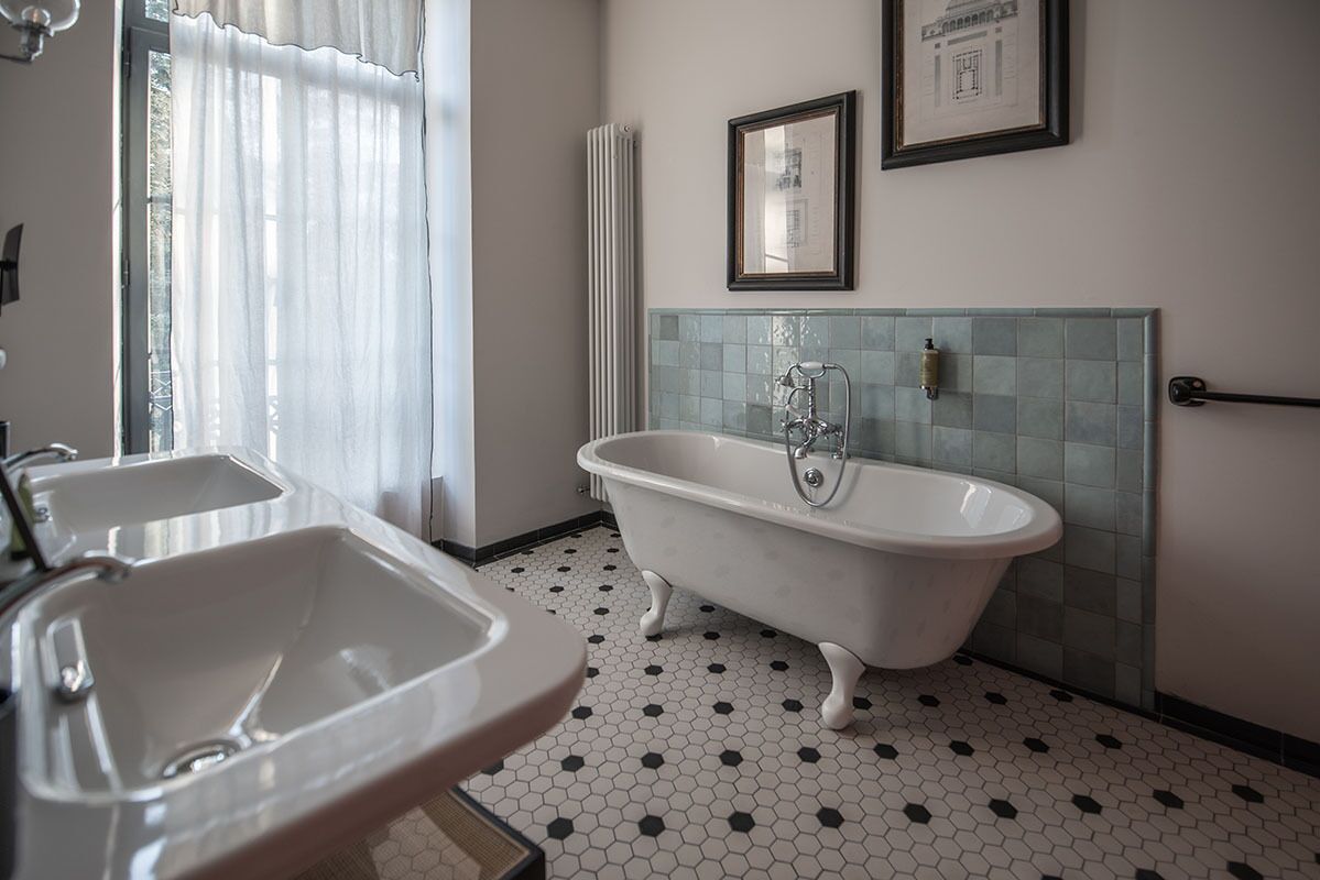 A bathroom with a white bathtub, two sinks, and a tiled floor.
