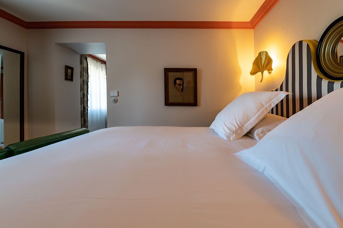 A hotel room with a large bed, a framed picture on the wall, and a decorative wall lamp.