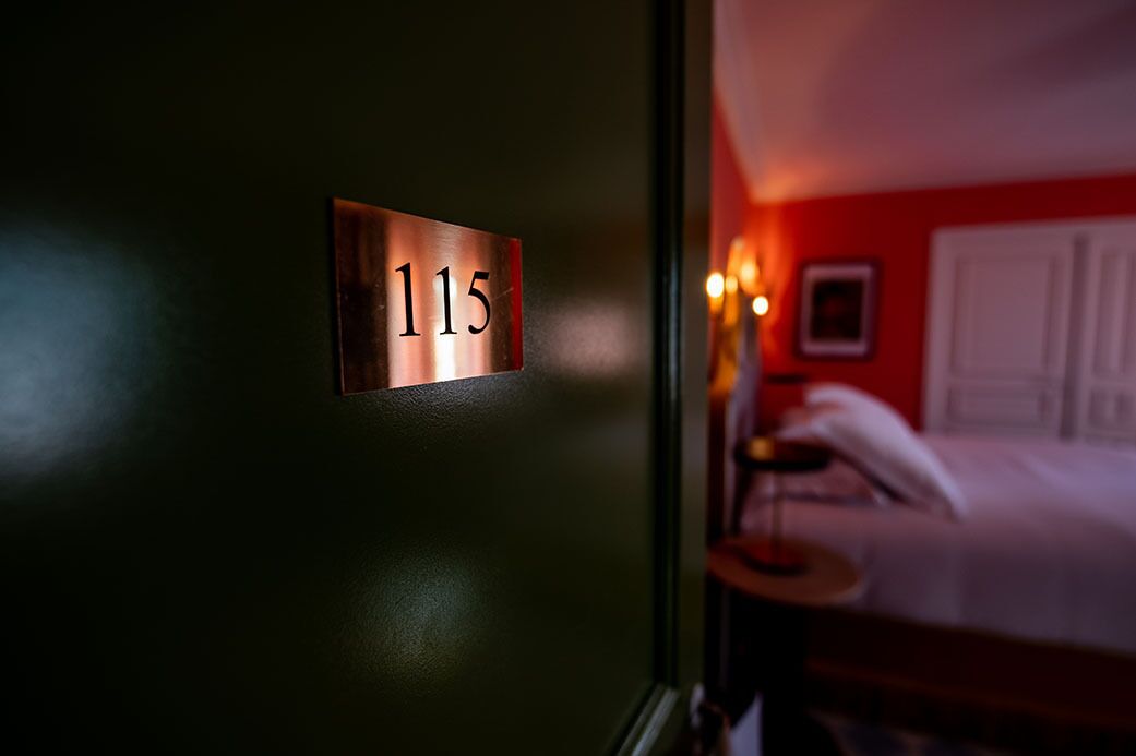 Habitación de hotel con una puerta que indica el número 115.