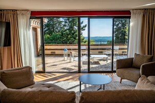 Amplia sala de estar con un gran ventanal corredero que da a una terraza exterior. La habitación cuenta con un sofá, una mesa de centro y un televisor montado en la pared.