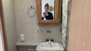 A compact bathroom with a toilet, sink, and wooden cabinet.