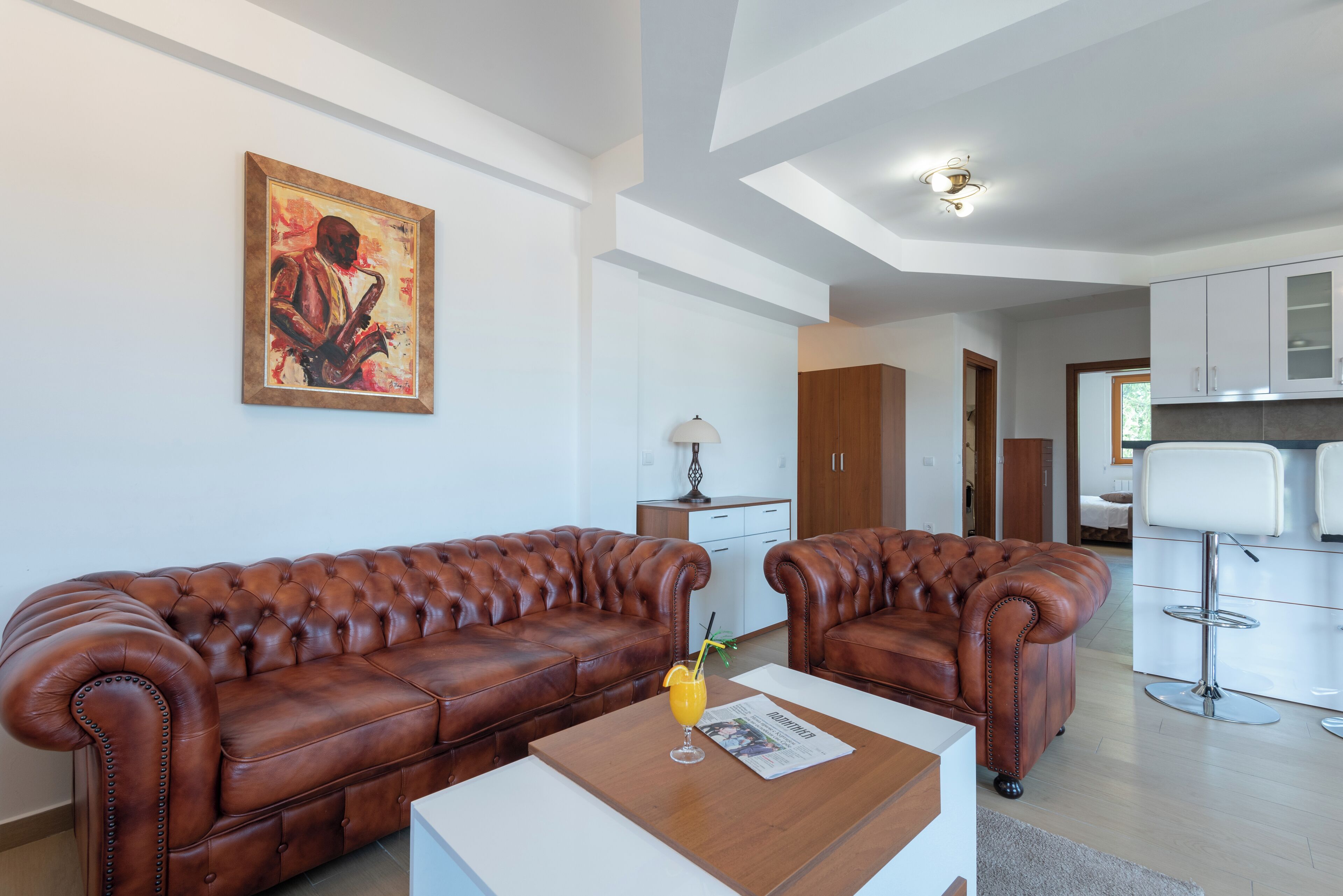 Ein modernes Wohnzimmer mit einem braunen Ledersofa, einem weißen Couchtisch und einem Gemälde an der Wand.