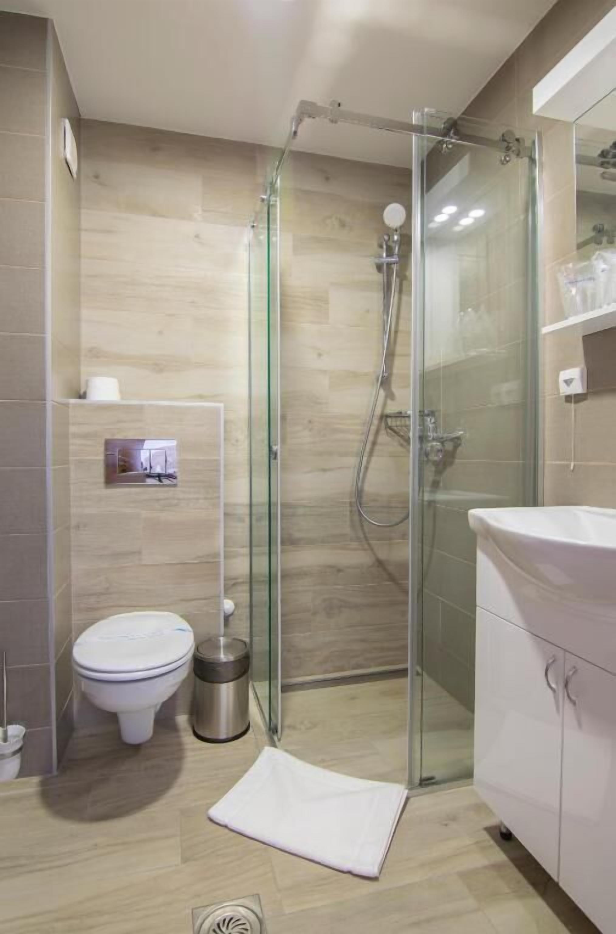 A modern bathroom with a glass-enclosed shower, a toilet, and a sink.