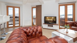 Een moderne woonkamer met een leren bank, een flatscreen televisie en een eethoek.