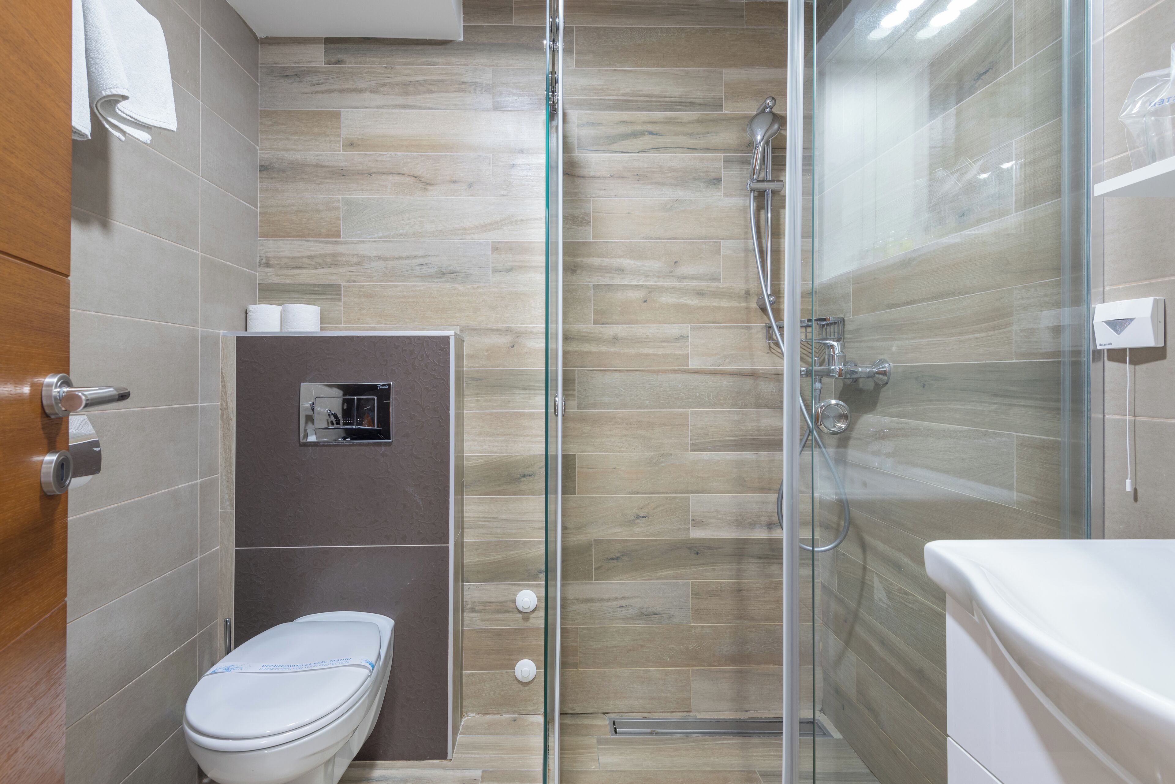 Un baño moderno con ducha acristalada, inodoro y lavamanos.