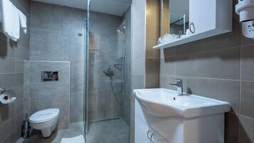 A modern bathroom with a glass-enclosed shower, a white sink, and a toilet.