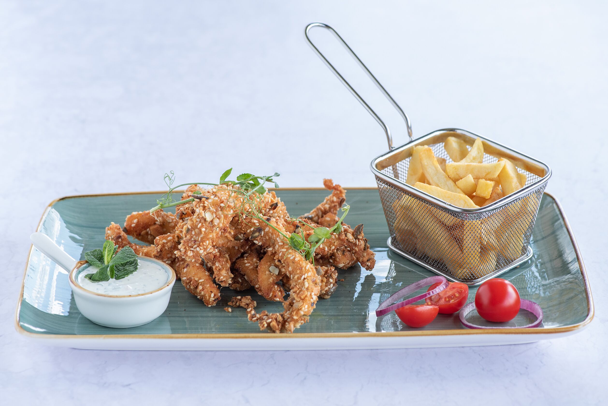 Un plato de pollo frito acompañado de papas fritas y salsa para mojar.