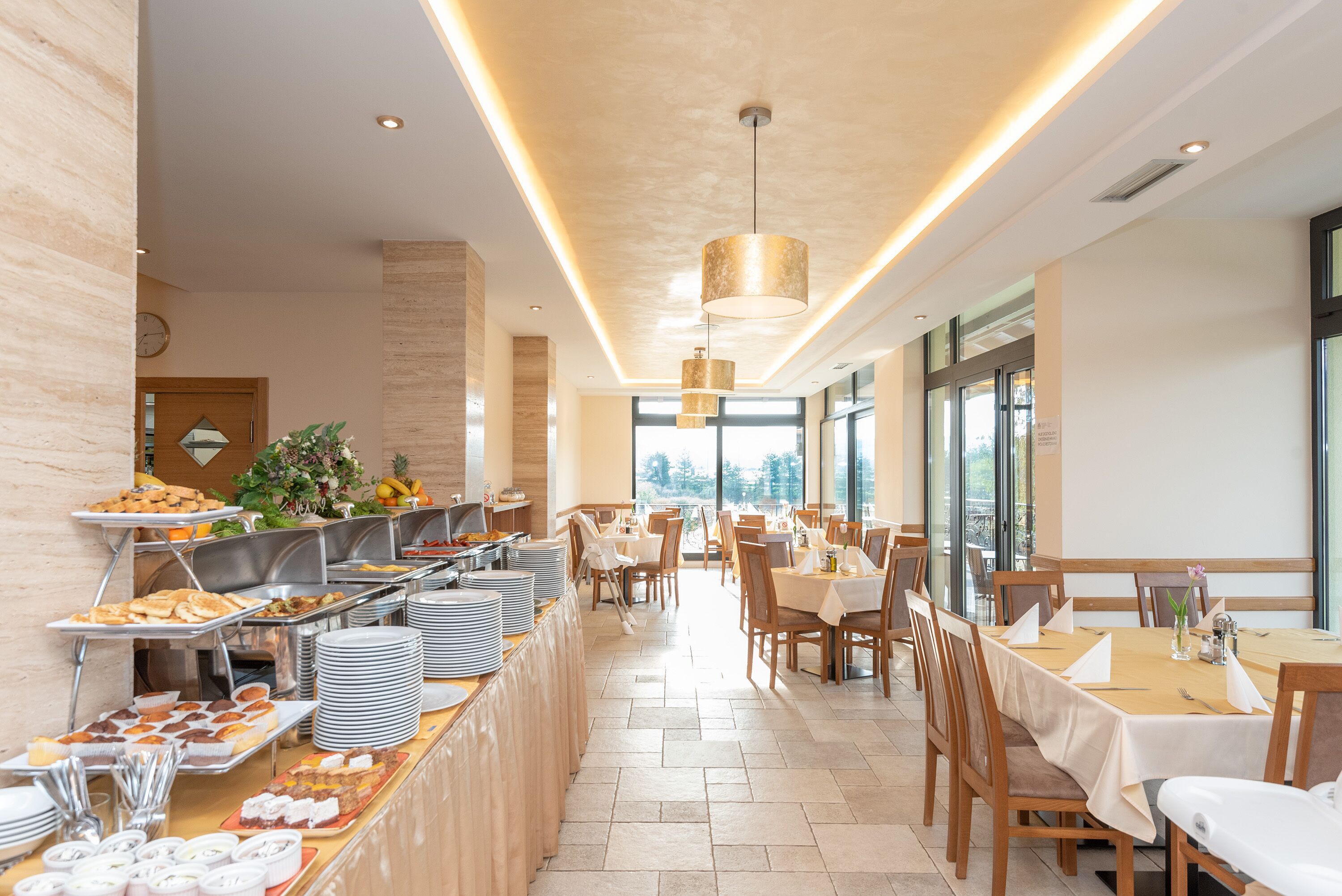 A buffet area with various food items and a dining section with tables and chairs.