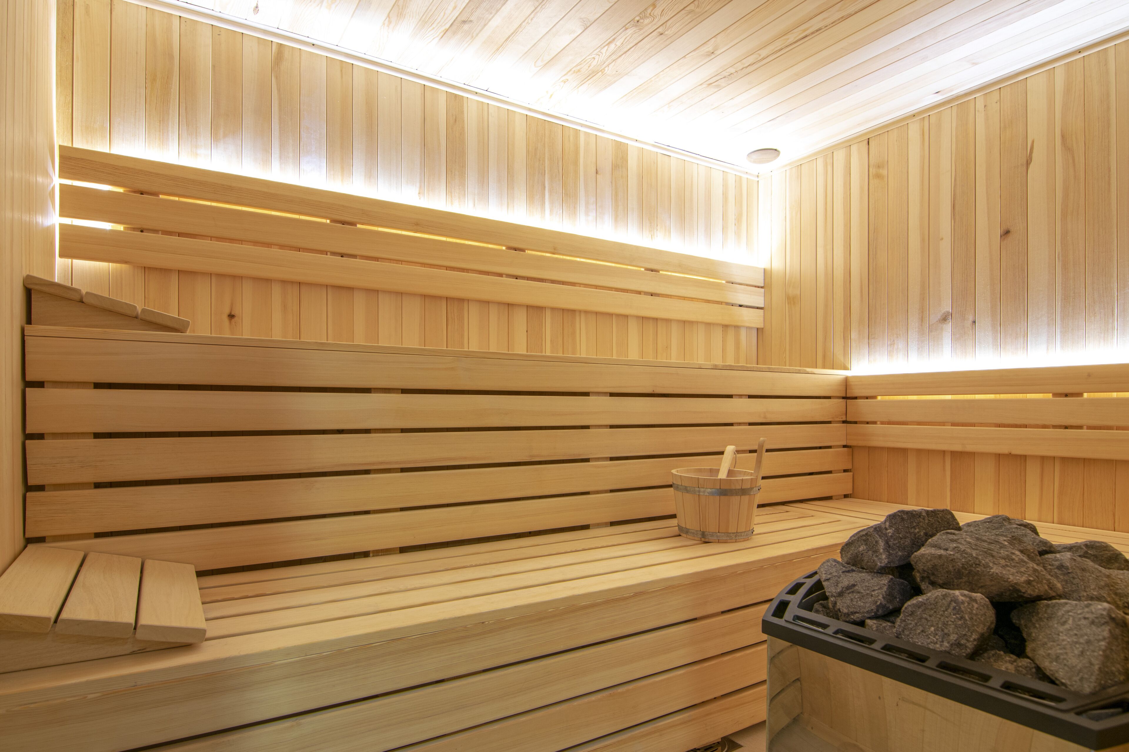 Eine Holzsauna mit Bänken und einem Steingefäß.