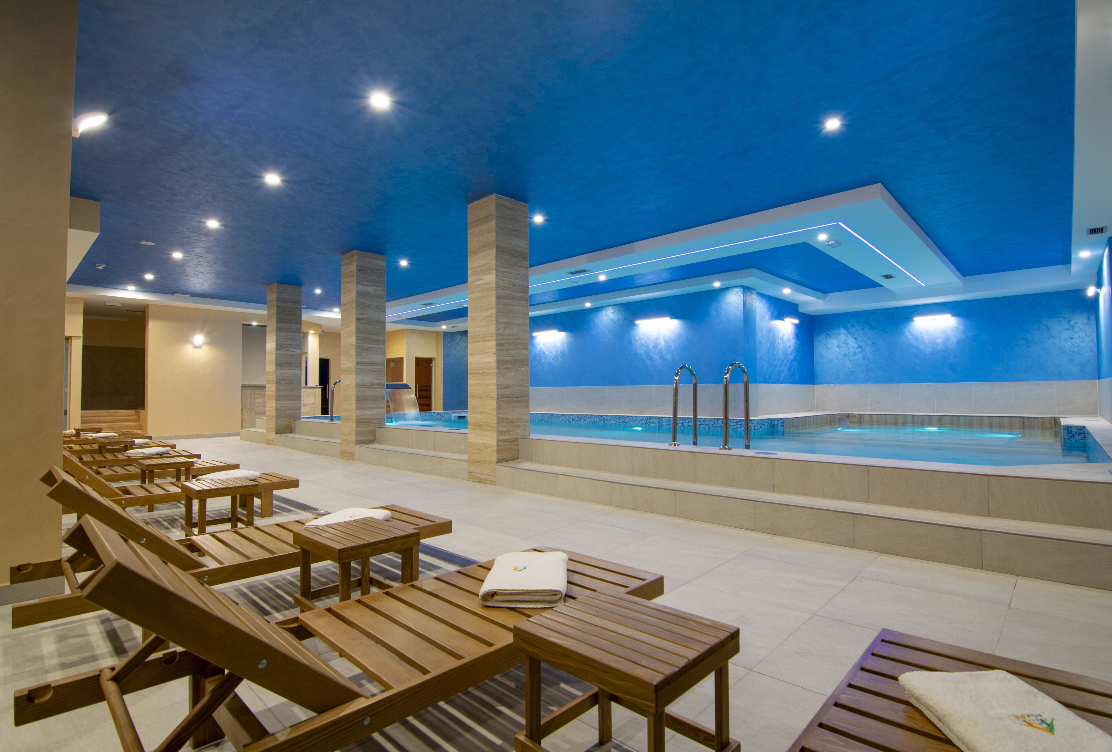 Un área de spa con tumbonas de madera y una piscina.
