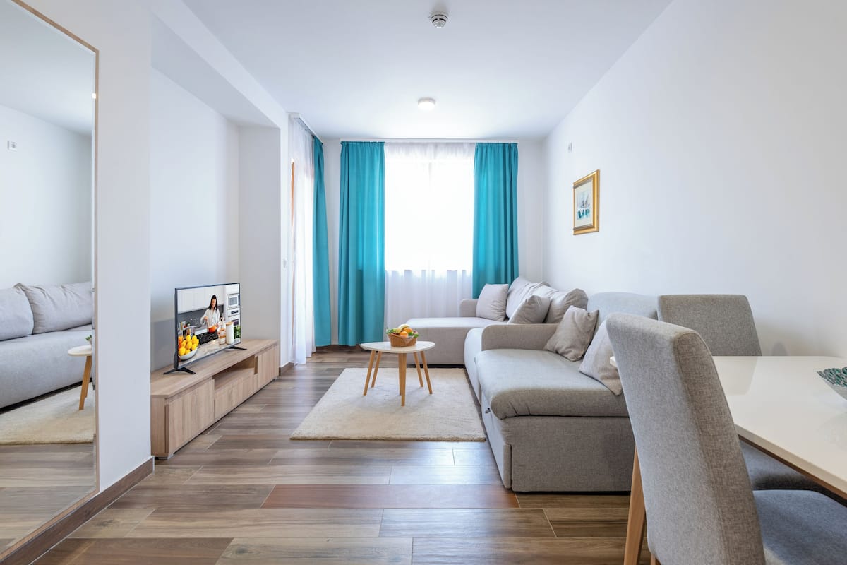 A modern living room with a sofa, a TV, and a dining area.