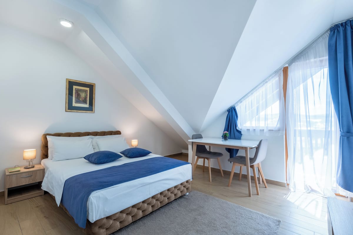 A bedroom with a bed, bedside table, and a desk with chairs.