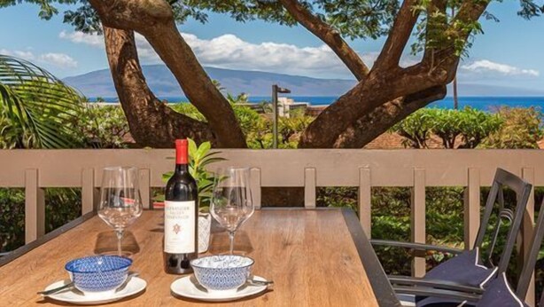 An outdoor dining area with a table set for two, a bottle of wine, and two glasses.