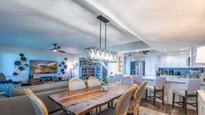 A modern kitchen with white cabinets, a central island, and a dining area with a wooden table and chairs.